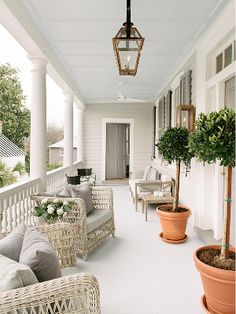 the front porch is decorated with wicker furniture and potted plants