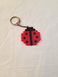 a red and black beaded ladybug keychain sitting on top of a white sheet