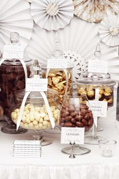 a table topped with lots of different types of candies and nuts next to paper fans