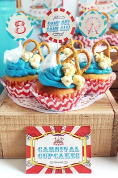 cupcakes with blue frosting and pretzels on top are sitting on a wooden box