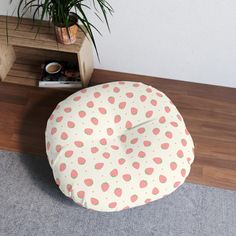 a floor pillow with strawberries on it next to a potted plant and bookshelf