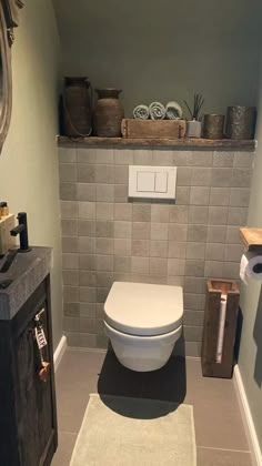 a white toilet sitting inside of a bathroom next to a wooden cabinet and towel dispenser