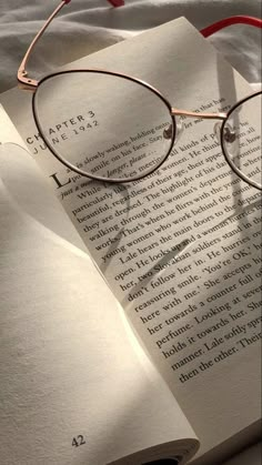 an open book with glasses on top of it