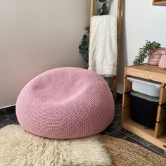 a pink bean bag sitting on top of a white rug next to a wooden shelf