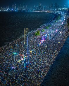 a large group of people standing on top of a beach next to the ocean