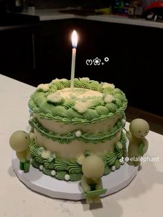 a birthday cake with green icing and two small figures on the side, sitting on a table