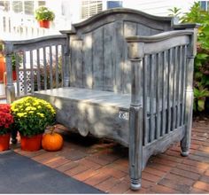 a wooden bench sitting on top of a brick walkway next to potted plants and pumpkins