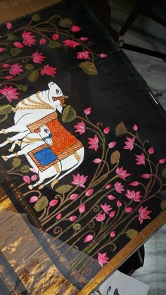 an embroidered cloth is laying on top of a table with flowers and leaves around it