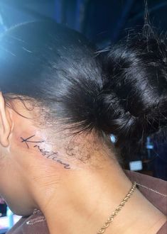 the back of a woman's head with a small tattoo on her left ear