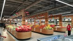 people are shopping in the produce section of a grocery store with large wooden baskets filled with fruits and vegetables