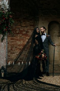 a man and woman standing next to each other in front of a brick wall with candles