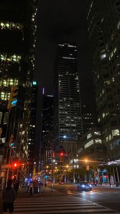 a city street at night with tall buildings in the background