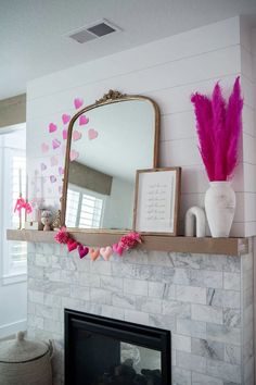 a fireplace with a mirror and pink decorations on it