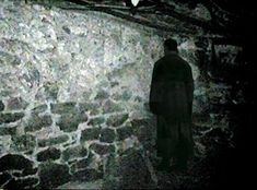 a man standing in front of a stone wall