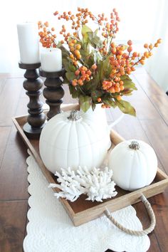 a wooden tray with white pumpkins and flowers in it on top of a table