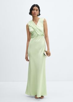 a woman wearing a green dress with a ruffled neckline and side slits