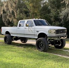 a white truck parked on top of a lush green field