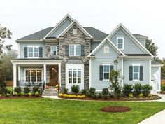 a house that is in the middle of some grass and flowers on the front lawn