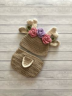 two crocheted hats with flowers on them sitting on a wooden floor next to each other