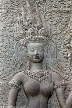 an intricately carved stone wall with a woman holding a flower in one hand and a bird on the other