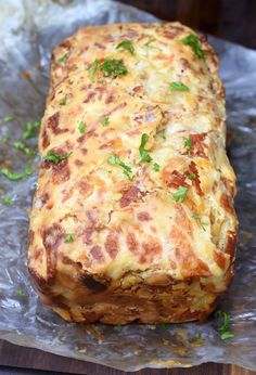 a cheesy meatloaf sitting on top of foil covered in parsley