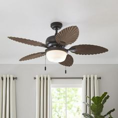 a ceiling fan in a living room with curtains