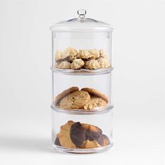 three tiered glass container with cookies and muffins in it on a white background