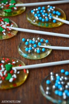 several spoons with candy on them are sitting on a table next to some lollipop sticks