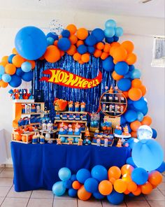 an orange and blue birthday party with balloons, streamers, and candy bar decorations