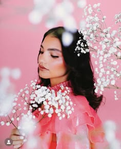 a woman with flowers in her hair is looking down at the ground and she has long black hair