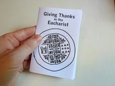 a person holding up a book with the title giving thanks in the eucharist