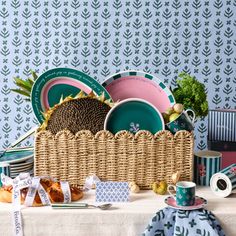 a table topped with plates and bowls next to a basket filled with fruit on top of a table