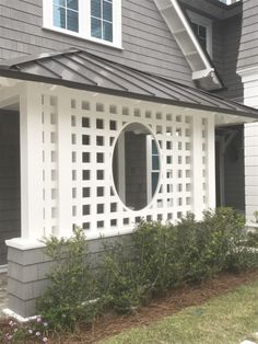 a gray house with a round window and white trim on the side of the house