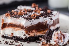 a piece of cake on a white plate with chocolate and whipped cream toppings in the middle