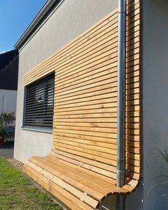 a wooden bench sitting in front of a building next to a grass covered lawn area