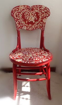 a red and gold painted chair against a white wall