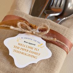 a napkin with a tag on it sitting next to a fork and knife in front of a plate