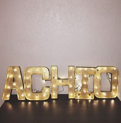 lighted letters spelling the word achio on a table in front of a wall