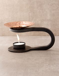 a candle that is sitting on top of a metal stand with a wooden plate on it