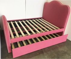 a pink bed frame with wooden slats