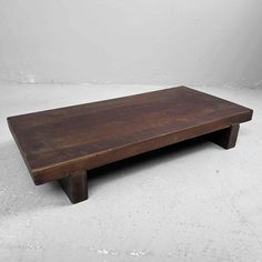 a wooden coffee table sitting on top of a white floor next to a gray wall