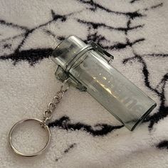 an empty glass jar sitting on top of a white rug next to a metal keychain