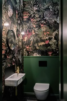 a toilet and sink in a small room with green wallpaper on the walls behind it