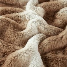 the fur is brown and white on top of the bedding sheets, which are very soft