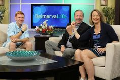 three people are sitting on couches in front of a television with the words delmarval life written on it