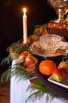 a table topped with plates covered in fruit next to a lit candle