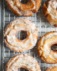 four glazed donuts sitting on top of a cooling rack with sprinkles