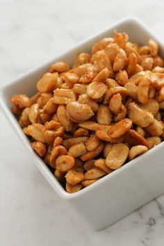 honey roasted peanuts in a square white bowl with text overlay that reads, honey roasted peanuts