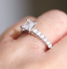 a close up of a person's hand with a diamond ring on their finger