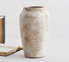 a book and vase sitting next to each other on a white table with an open book